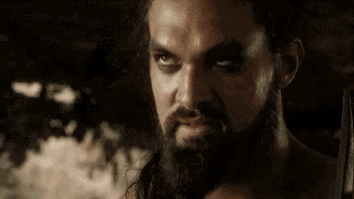 a man with a beard and long hair is looking down .