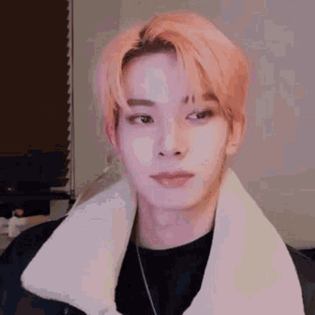 a close up of a person with pink hair wearing a white jacket and a black shirt .
