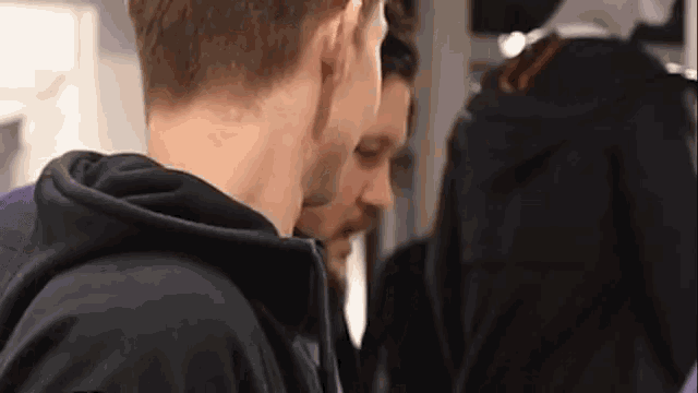 a man in a black hoodie is standing next to another man in a black jacket
