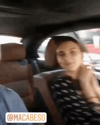 a woman is sitting in the back seat of a car with a sticker that says macabeso on it