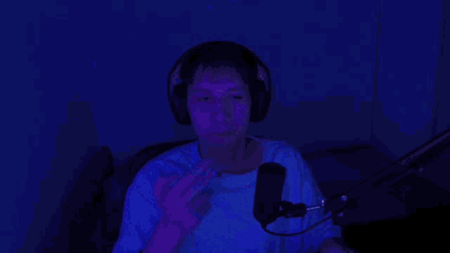 a man wearing headphones is smoking a cigarette in front of a microphone