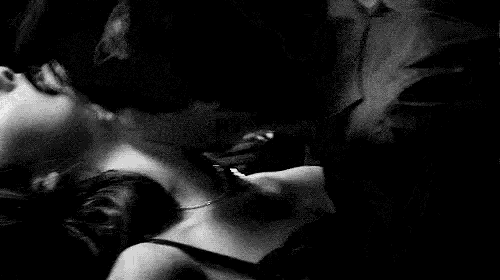 a black and white photo of a man and woman kissing .