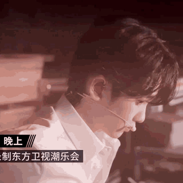 a man wearing a white shirt and a microphone with chinese writing on the bottom right