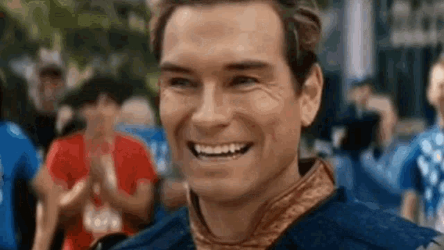 a man is smiling in front of a crowd of people while wearing a blue jacket .