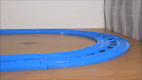 a toy train is going around a blue track on a table