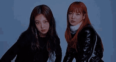 two women are standing next to each other in a dark room .
