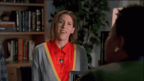 a woman in a red shirt and a gray sweater is waving at another woman .