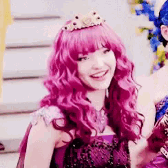 a woman with pink hair and a crown on her head is smiling .