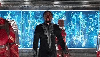a man in a black suit is standing in front of a wall with a blue background .