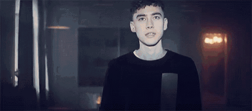 a young man is standing in a dark room with his eyes closed and his mouth open .
