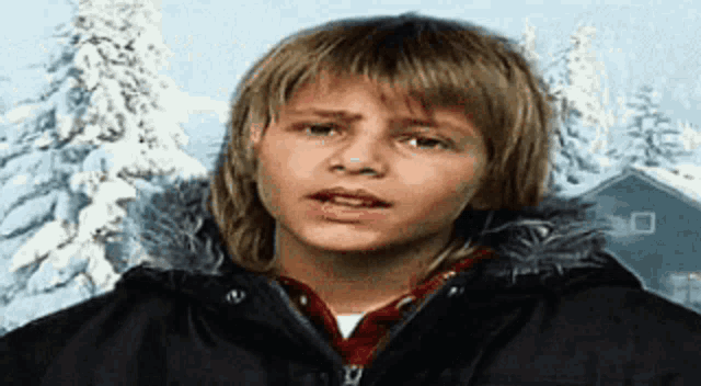 a young boy with long blonde hair is wearing a black jacket and a red shirt .
