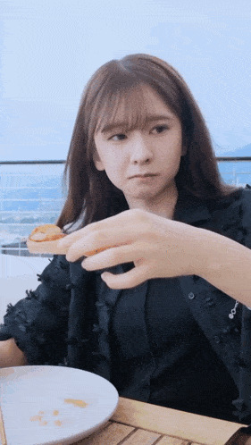 a woman sitting at a table eating a piece of food