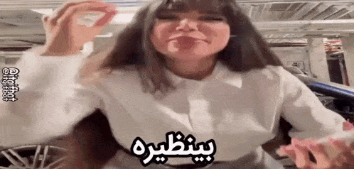 a woman in a white shirt is making a funny face in a parking garage .