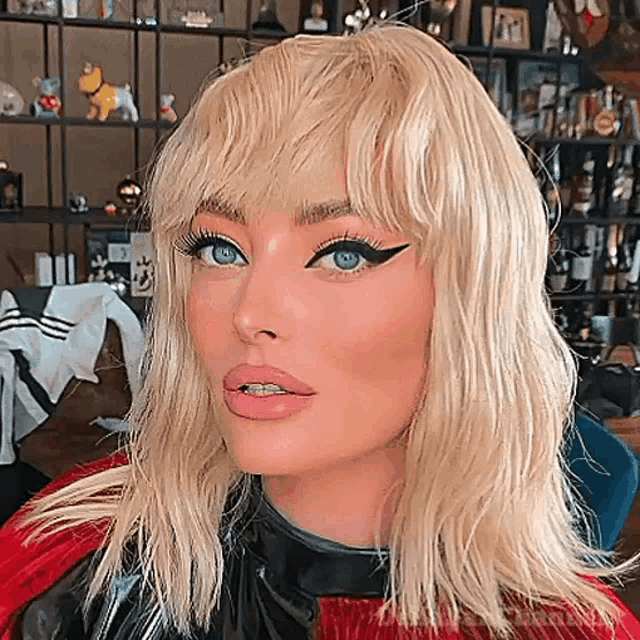 a woman with blonde hair and blue eyes is wearing a black leather jacket