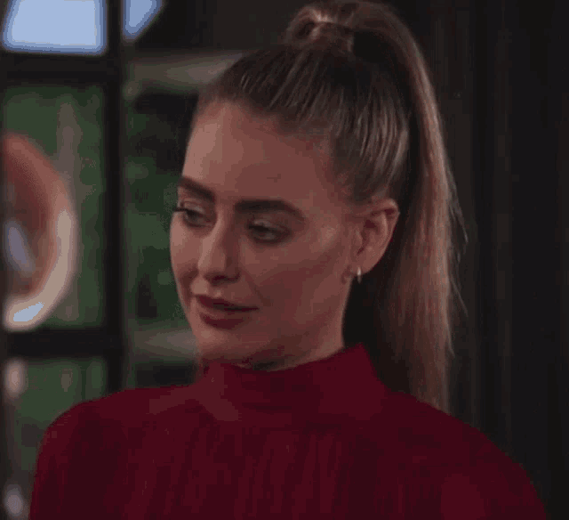 a woman with a ponytail is wearing a red top