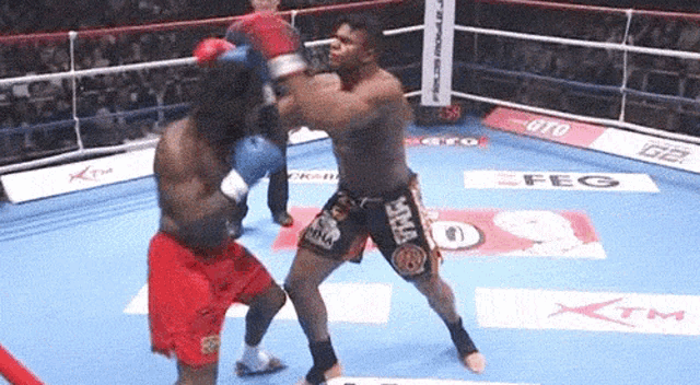 two boxers are fighting in a ring and one of them is wearing shorts that say mma