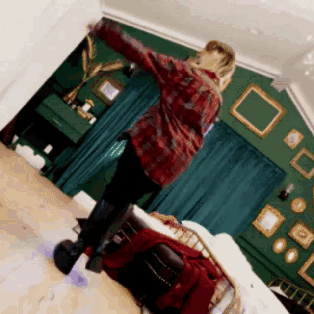 a woman in a red plaid shirt is dancing in a bedroom