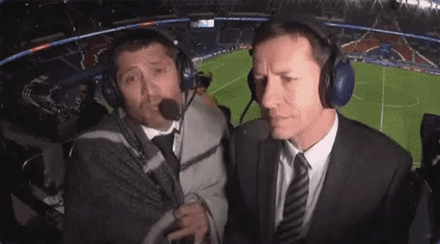 two men wearing headphones are talking to each other in a stadium .