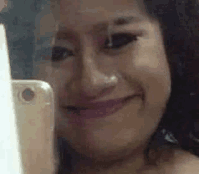 a woman is smiling while taking a selfie with her cell phone .