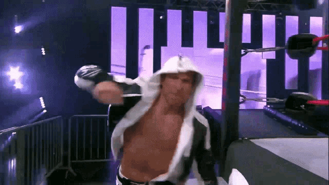 a man in a white hooded robe stands in front of a wrestling ring