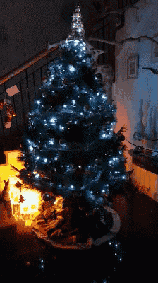 a christmas tree with blue lights is lit up in a living room