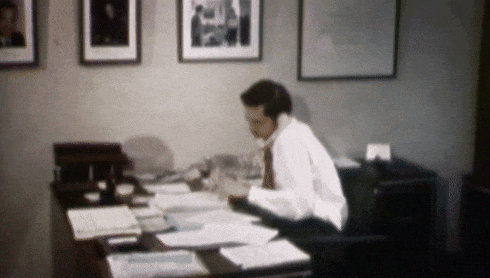 a man sits at a desk talking on the phone
