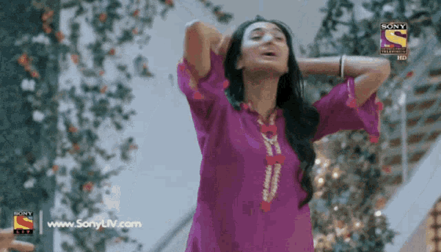a woman in a purple dress is dancing in front of a sign that says sony tv