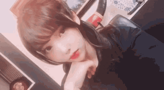 a girl is taking a selfie with her hand on her chin .