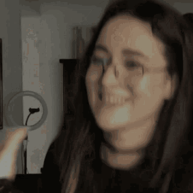 a woman wearing glasses and a choker is smiling in a dark room