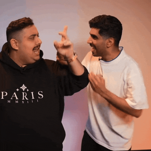 two men are standing next to each other and one is wearing a paris sweatshirt