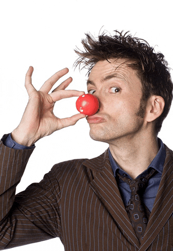 a man in a suit and tie holds a red clown nose