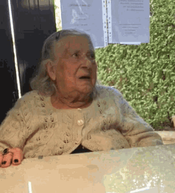 an elderly woman sits at a table in front of a sign that says ' alzheimer 's ' on it