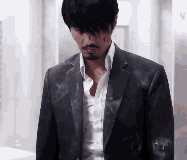 a man with a beard is wearing a suit and white shirt