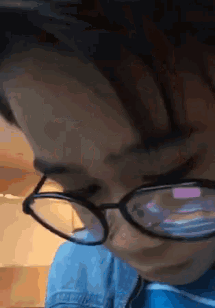 a person wearing glasses looks down at something