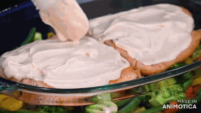 a casserole dish filled with chicken and vegetables is being made by animatica