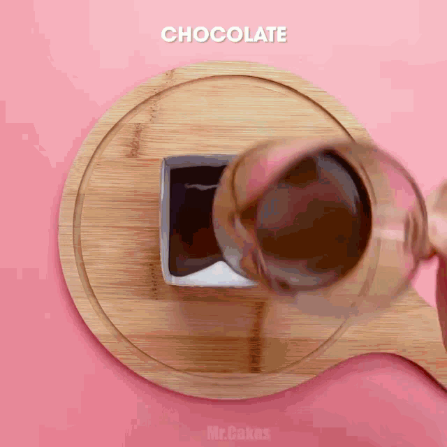 a person pouring chocolate into a glass on a wooden board