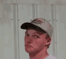 a man wearing a hat and a white shirt is making a funny face .