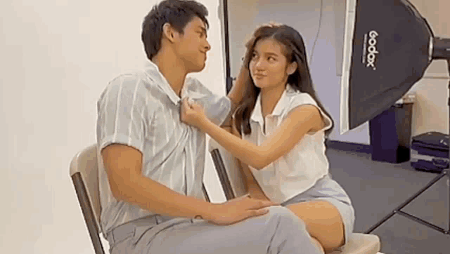 a man and a woman are sitting next to each other in a chair and touching each other .