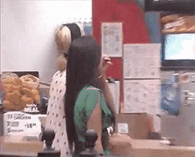 a woman in a green dress is standing in front of a counter in a restaurant .