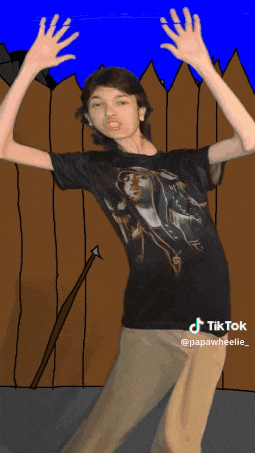 a boy in a black shirt is standing in front of a wooden fence with an arrow in his hand