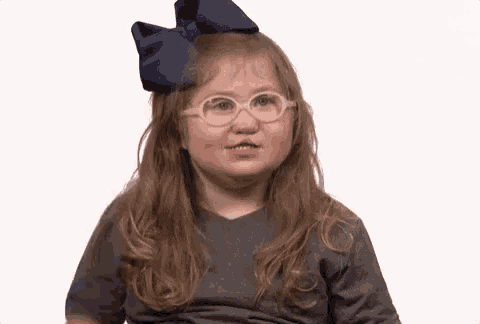 a little girl wearing glasses and a blue bow