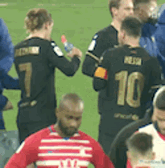 a group of soccer players standing on a field with one wearing a number 10 jersey