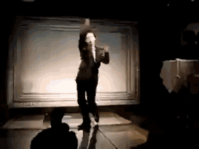 a man in a suit is dancing on a stage with a microphone in his hand