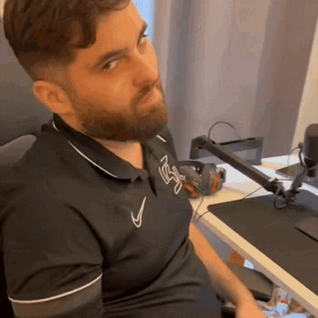 a man with a beard wearing a black nike polo shirt