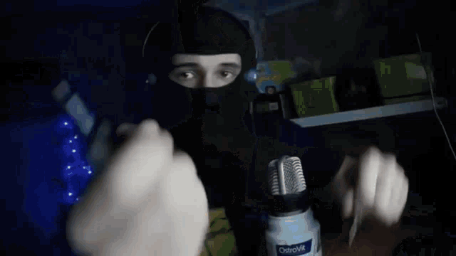 a man wearing a mask and headphones is holding a bottle of ostrovit
