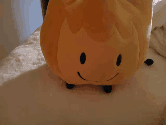 a stuffed animal that looks like a flame with a smile on its face