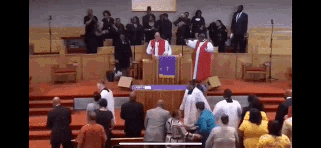 a group of people are standing in a church while a priest stands at the podium giving a sermon .