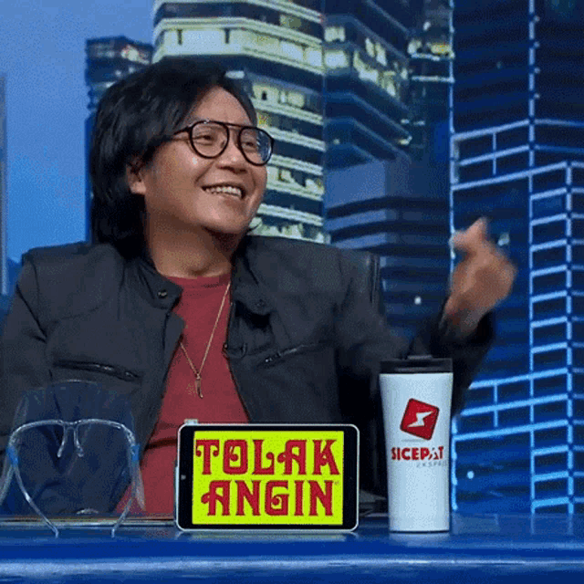 a man sitting at a desk with a tablet that says tolak angin