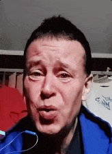 a man in a blue jacket is making a face