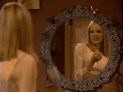 a woman is brushing her hair in front of a mirror with a floral frame .